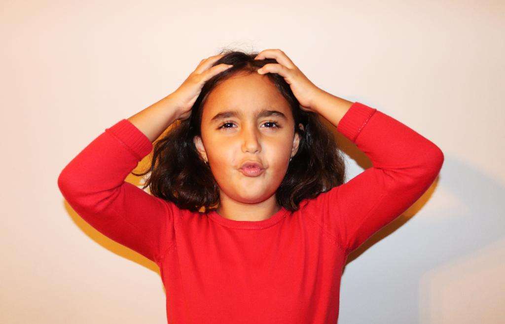 A young girl in a red sweater looking frustrated and bewildered.