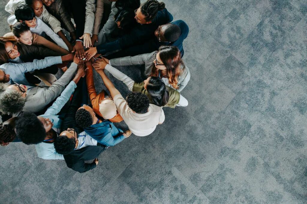 A diverse business team showing collaboration and unity with hands joined together in a team-building exercise.