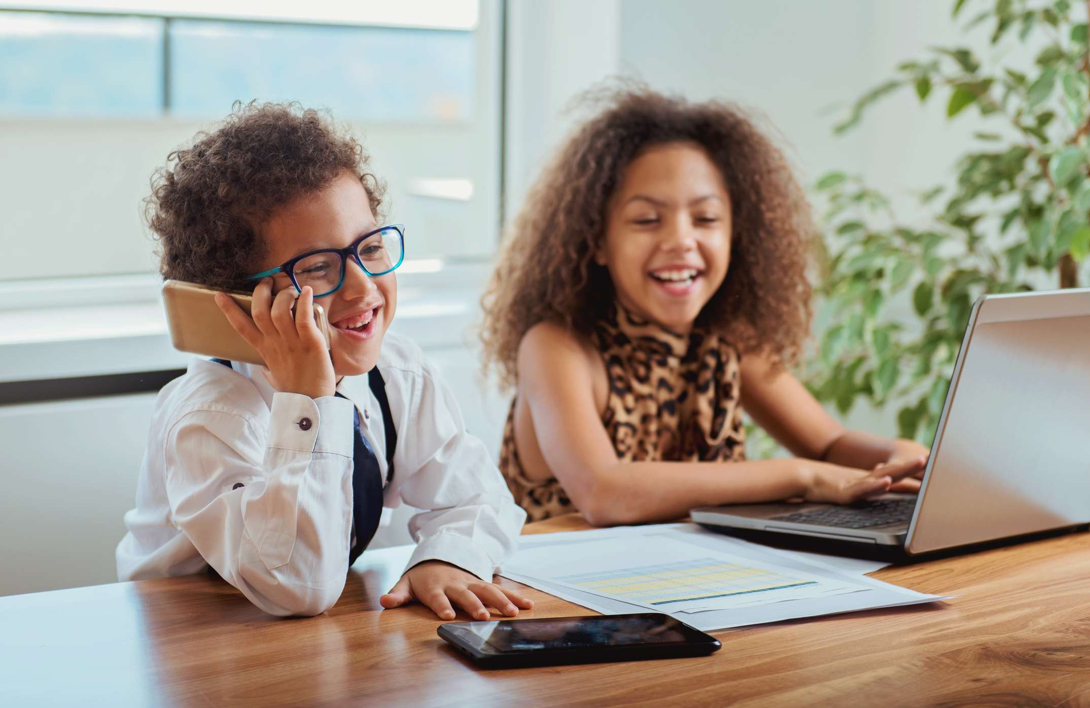 Two little kids laughing and working at a desk